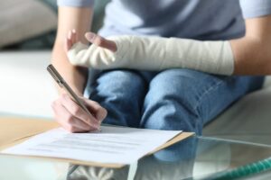 woman with bandaged arm signing a document