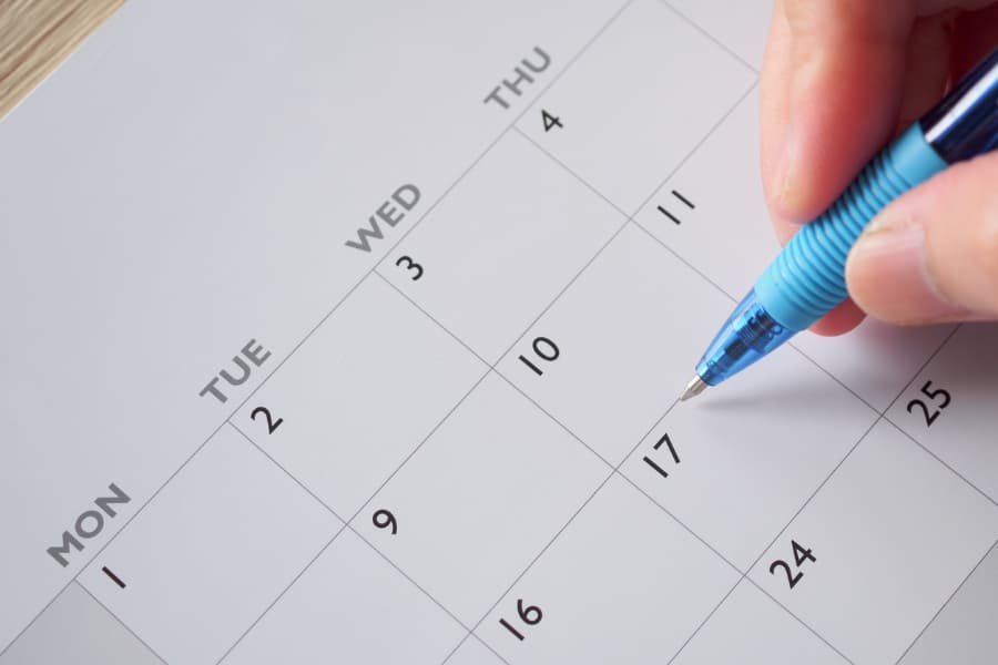 Close-up of a calendar with a woman’s hand holding a blue pen