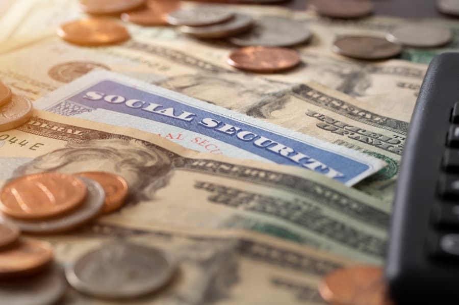 Close up of a Social Security card with $20 bills and change on top