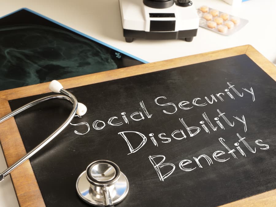 Social Security Disability written on a chalkboard with a stethoscope and medication in the background