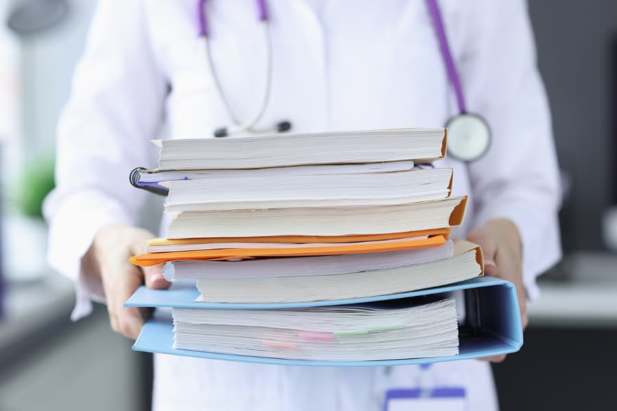 Blurred image of a doctor holding a large stack of papers