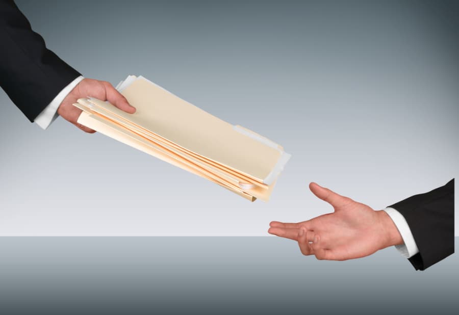 Close up of a man handing file folders and documents to another man