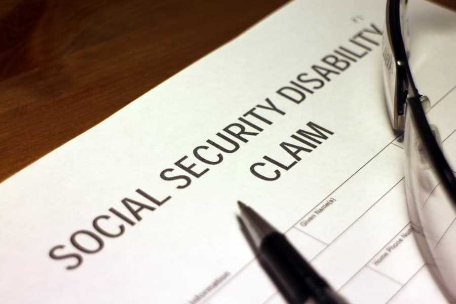 Close up of a Social Security Disability claim with a pen and eyeglasses on top