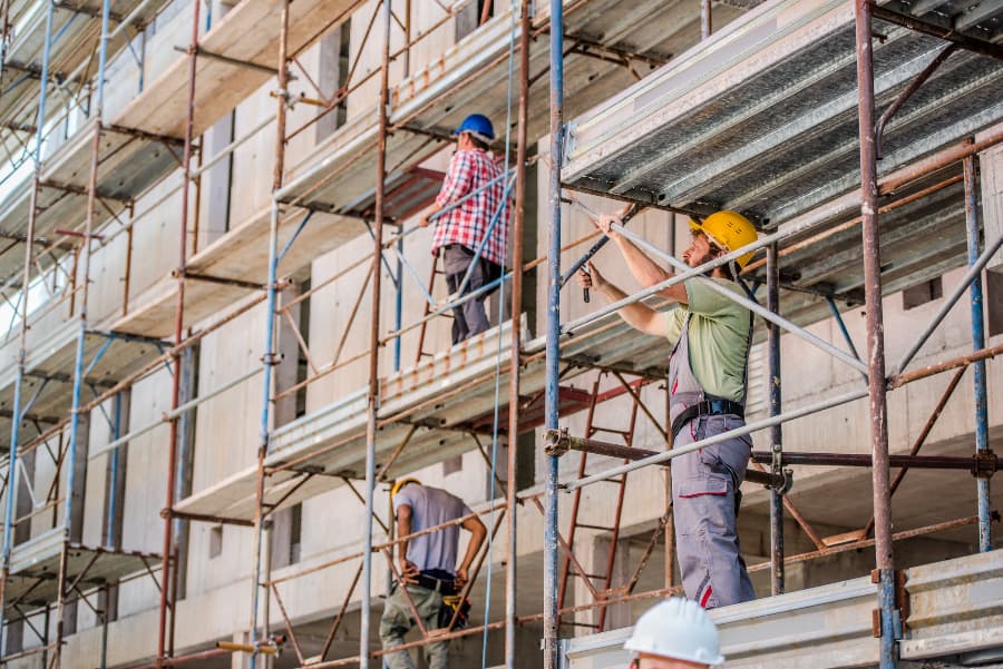 Three construction workers on scaffolding.