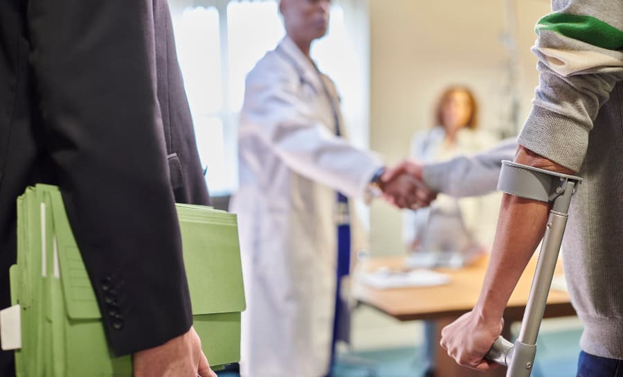 Blurred image of a lawyer carrying files and a disabled man shaking a doctor’s hand.