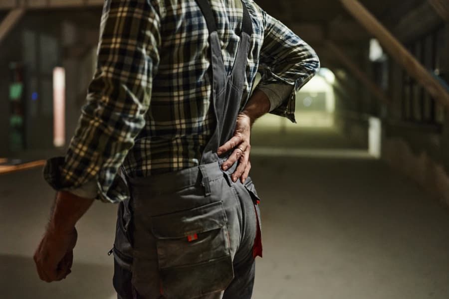 Side/rear view of an injured worker holding his lower back.